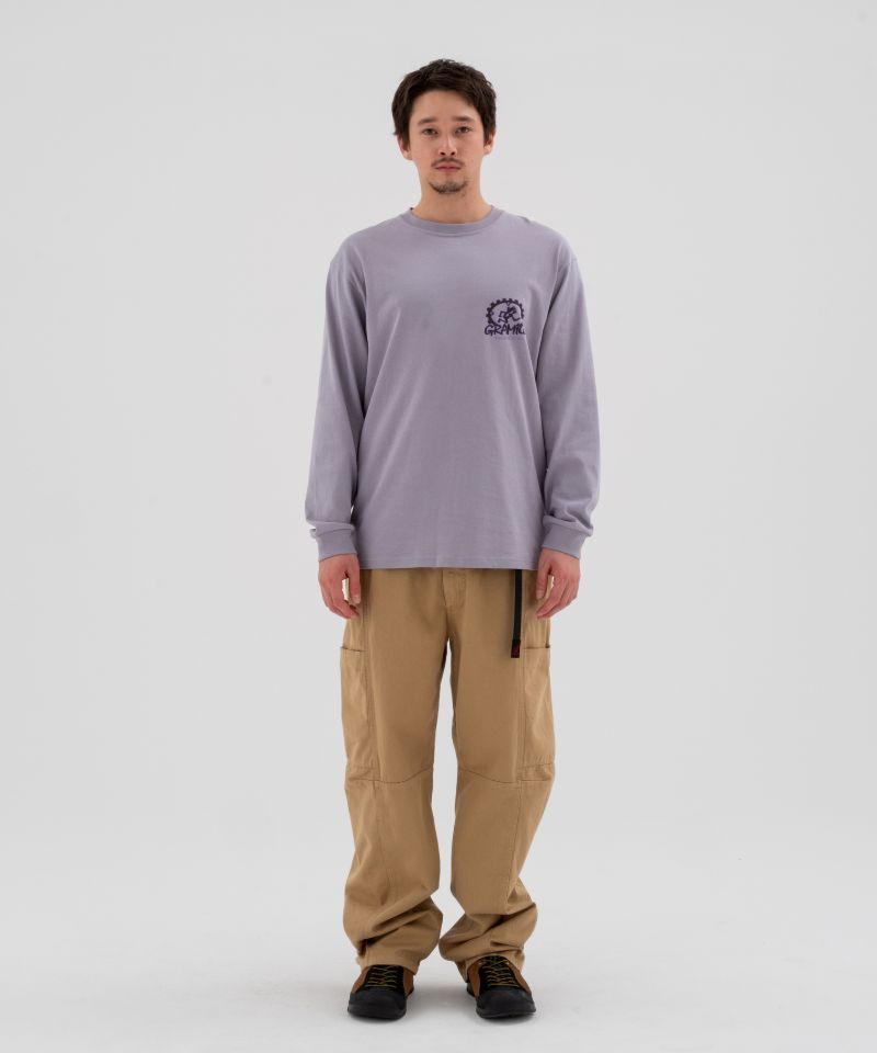 Model wearing beige Gramicci Voyager Pants and a lavender Gramicci Equipped Dirt Long-Sleeve-Tee on a light-tone background.