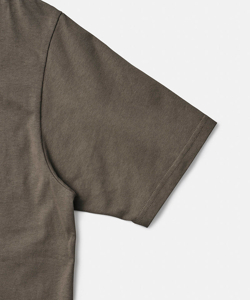 Close-up of a coyote brown Gramicci One Point Tee on a light-tone background.