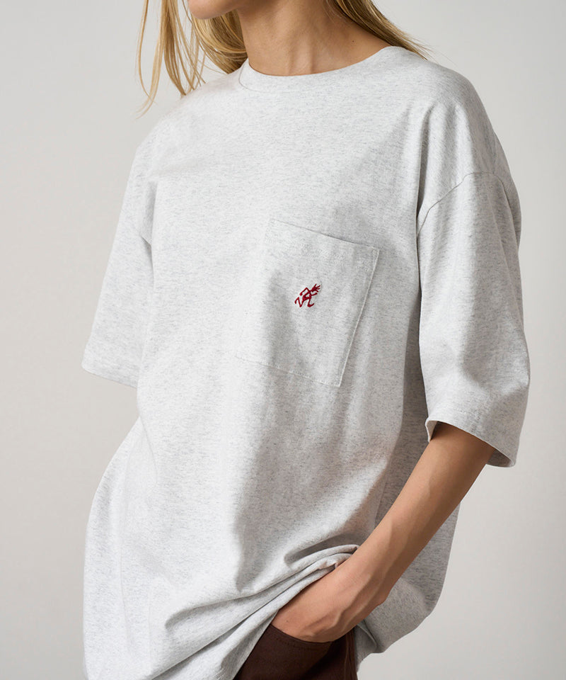 Model wearing a Gramicci heather ash One Point Tee with a small running man graphic against a light-tone background.