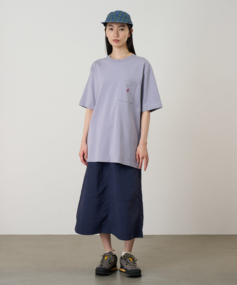 Model wearing a lavender Gramicci One Point Tee with a small running man graphic and blue skirt on a light-tone background.