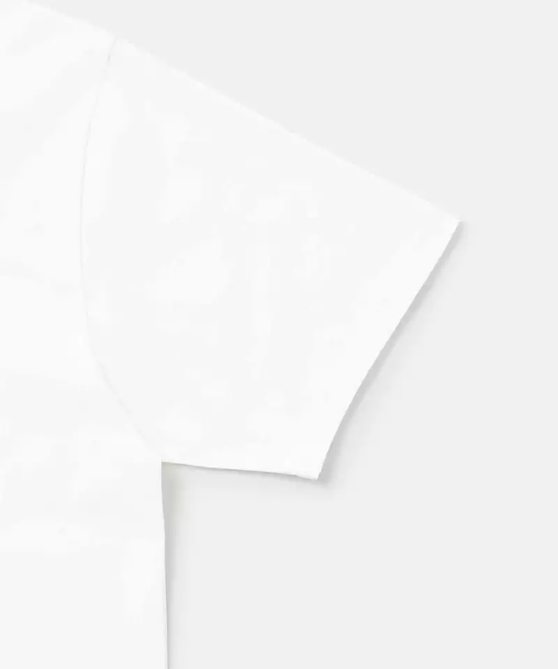 Close-up of a white Gramicci One Point Tee sleeve on a light-tone background.