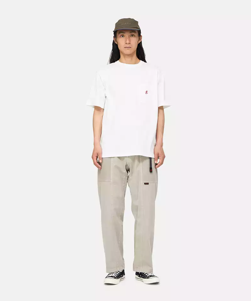 Model wearing a white Gramicci One Point Tee with a small running man graphic and beige pants on a light-tone background.