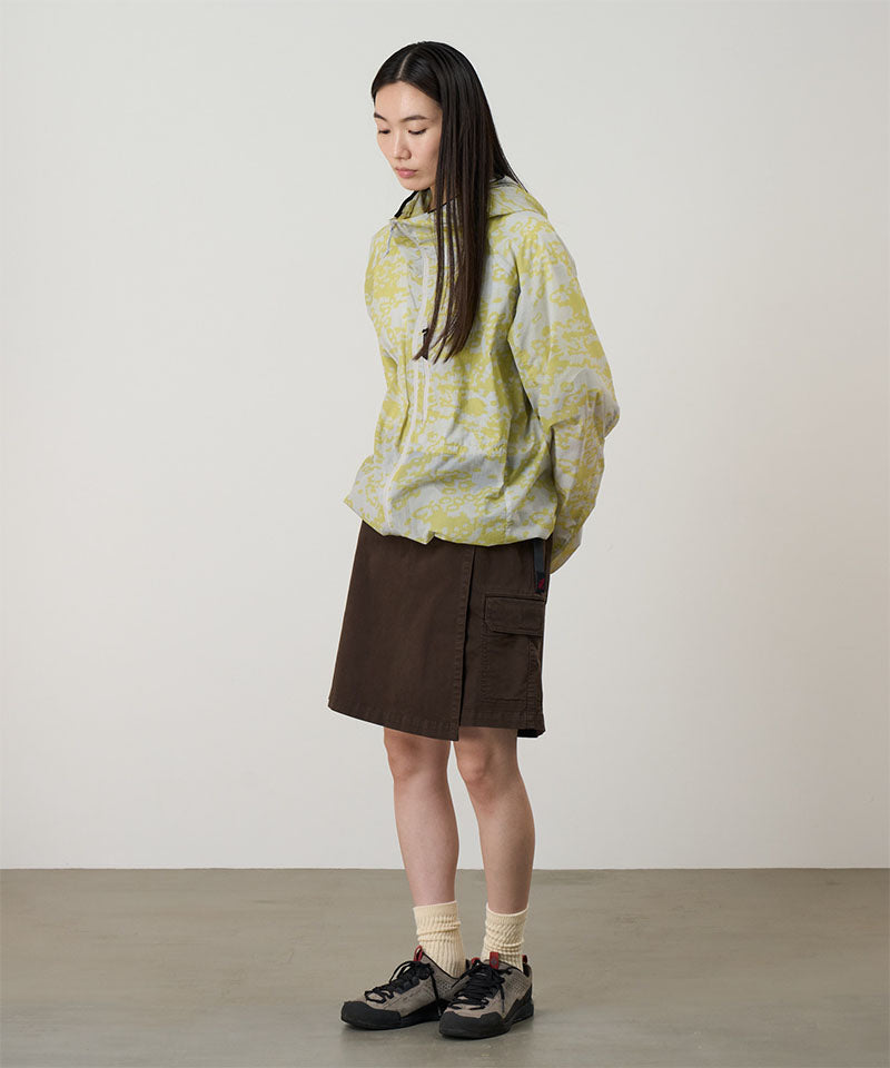 Model wearing a Gramicci G-Skort in the color chocolate and a yellow patterned jacket on a light-tone background.