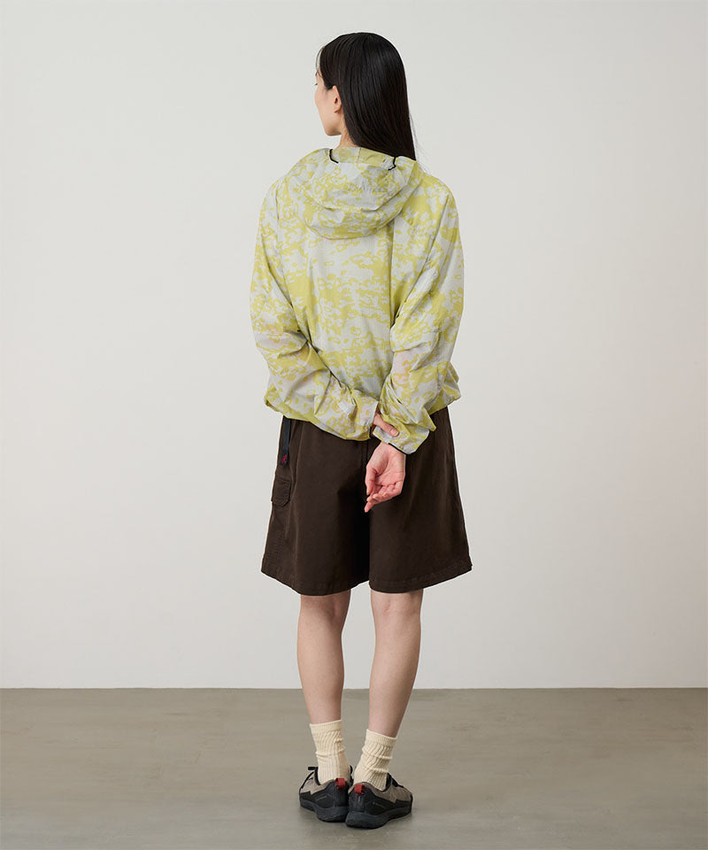 Back view of a model wearing a Gramicci G-Skort in the color chocolate and a yellow patterned jacket on a light-tone background.