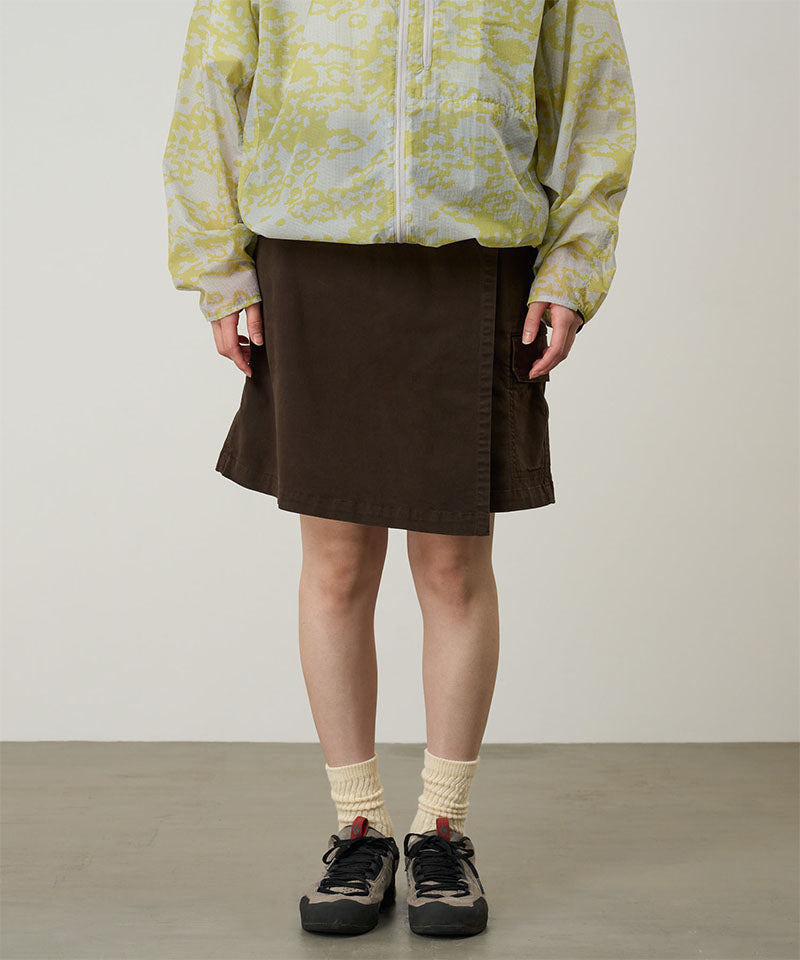 Model wearing a Gramicci G-Skort in the color chocolate and a yellow patterned jacket on a light-tone background.