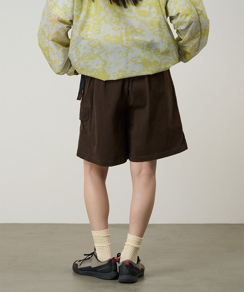 Back view of a model wearing a Gramicci G-Skort in the color chocolate and a yellow patterned jacket on a light-tone background.