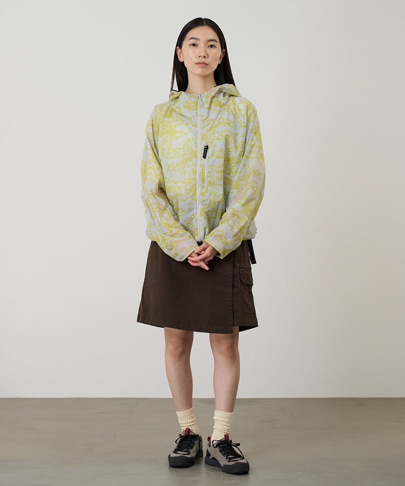 Model wearing a Gramicci G-Skort in the color chocolate and a yellow patterned jacket on a light-tone background.