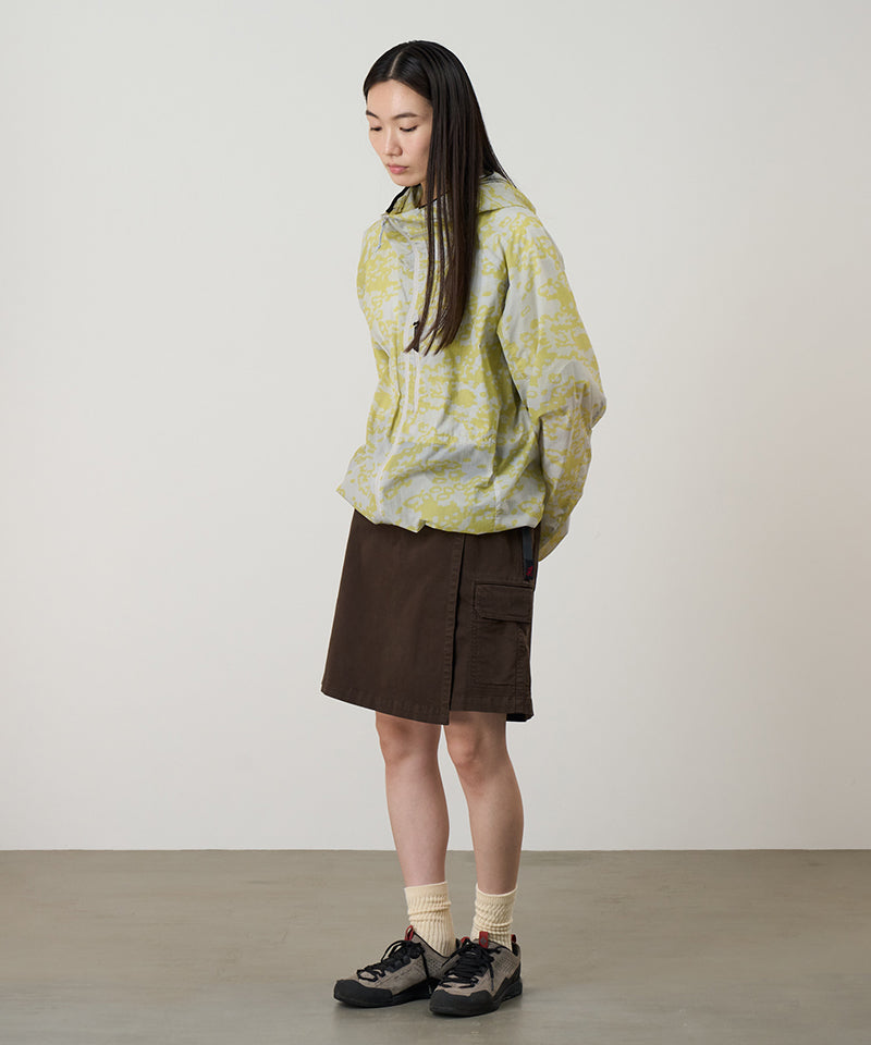 Model wearing a Gramicci G-Skort in the color chocolate and a yellow patterned jacket on a light-tone background.