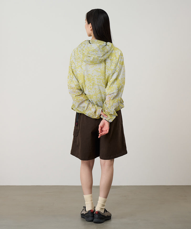 Back view of a model wearing a Gramicci G-Skort in the color chocolate and a yellow patterned jacket on a light-tone background.