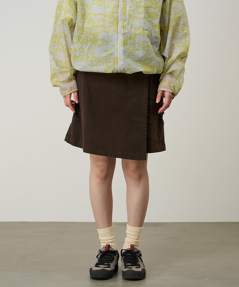 Model wearing a Gramicci G-Skort in the color chocolate and a yellow patterned jacket on a light-tone background.