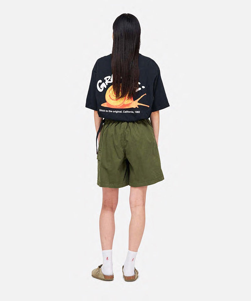 Back view of a model wearing a Gramicci G-Skort in the color olive and a black shirt on a light-tone background.