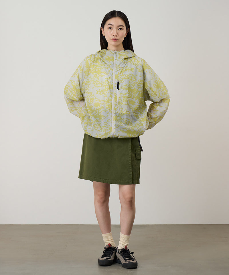 Model wearing a Gramicci G-Skort in the color olive and a yellow patterned jacket on a light-tone background.