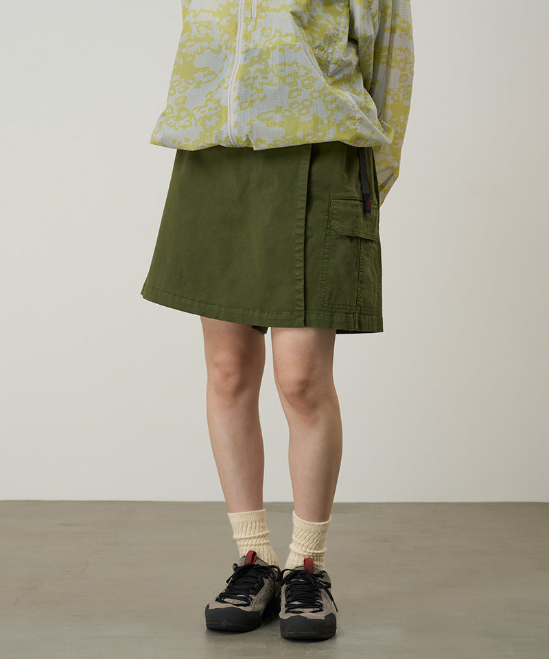 Model wearing a Gramicci G-Skort in the color olive and a yellow patterned jacket on a light-tone background.