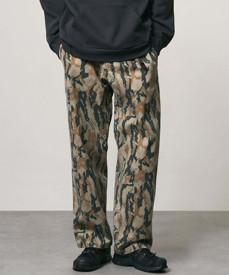 Model wearing bark camo Denim Gramicci Pant Straight Fit and a black hoodie on a light-tone background.
