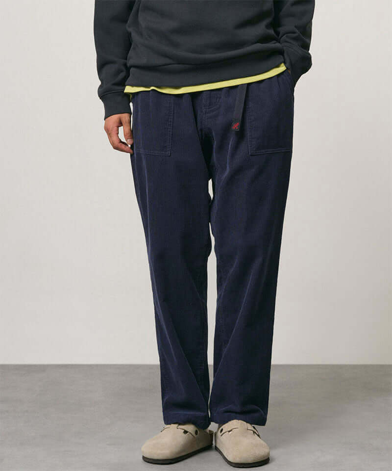 Model wearing dark navy Gramicci Corduroy Loose Tapered Ridge Pants and a black sweatshirt on a light-tone background.