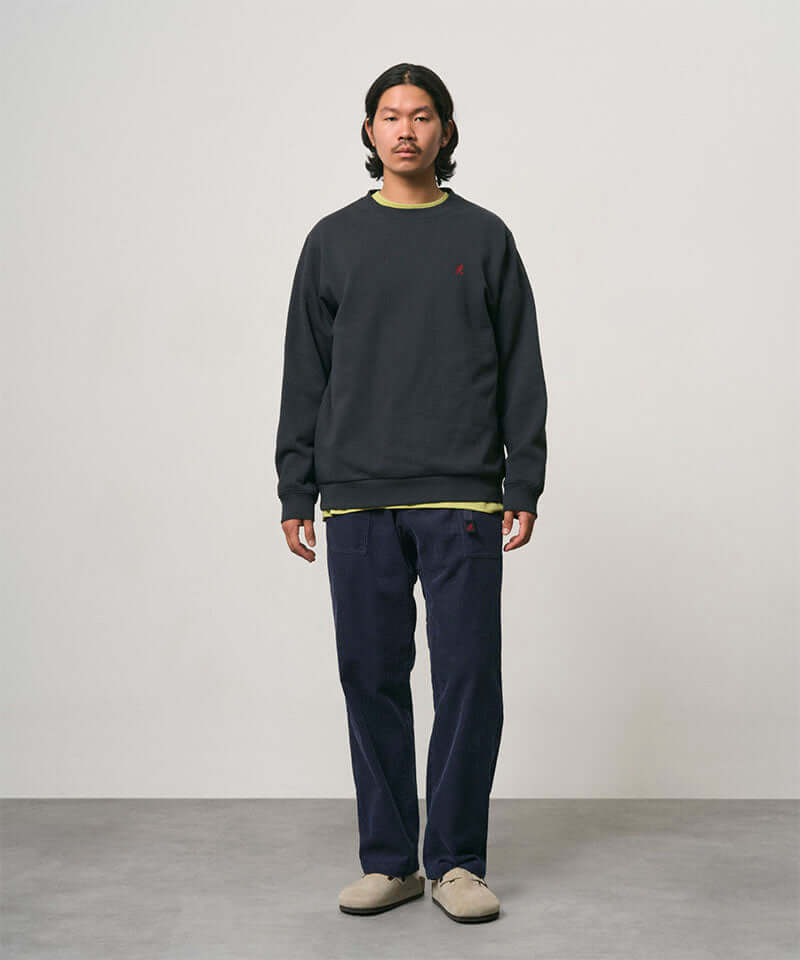 Model wearing dark navy Gramicci Corduroy Loose Tapered Ridge Pants and a black sweatshirt on a light-tone background.