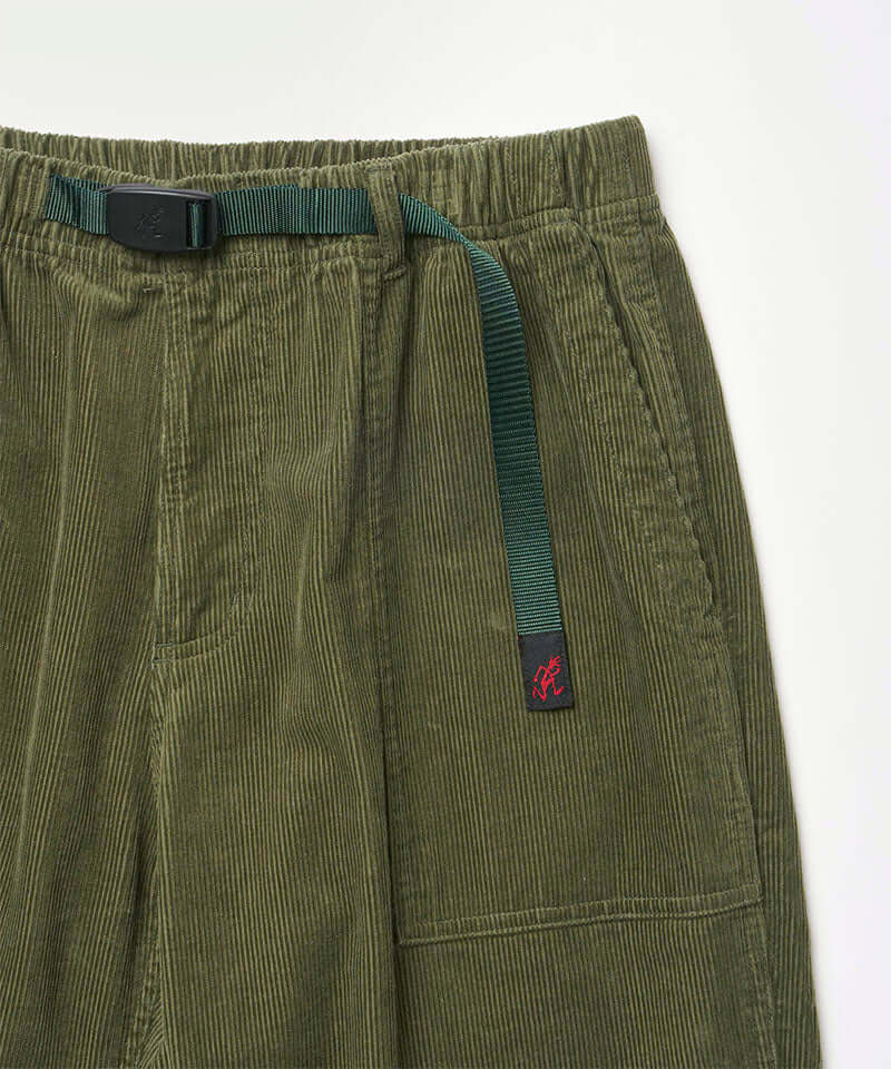 Close-up view of toned olive colored Gramicci Corduroy Loose Tapered Ridge Pants on a light-tone background.