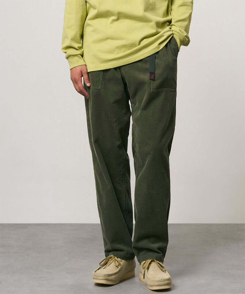 Model wearing toned olive colored Gramicci Corduroy Loose Tapered Ridge Pants and a lime green shirt on a light-tone background.
