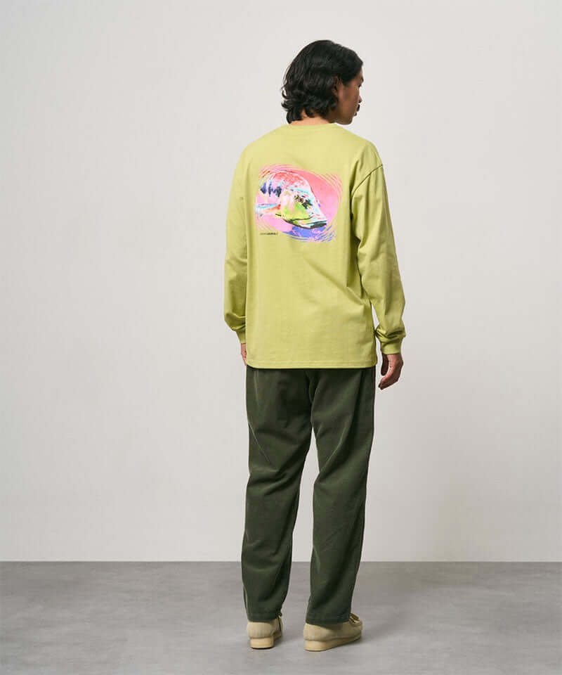 Back view of a model wearing toned olive colored Gramicci Corduroy Loose Tapered Ridge Pants and a lime green shirt on a light-tone background.