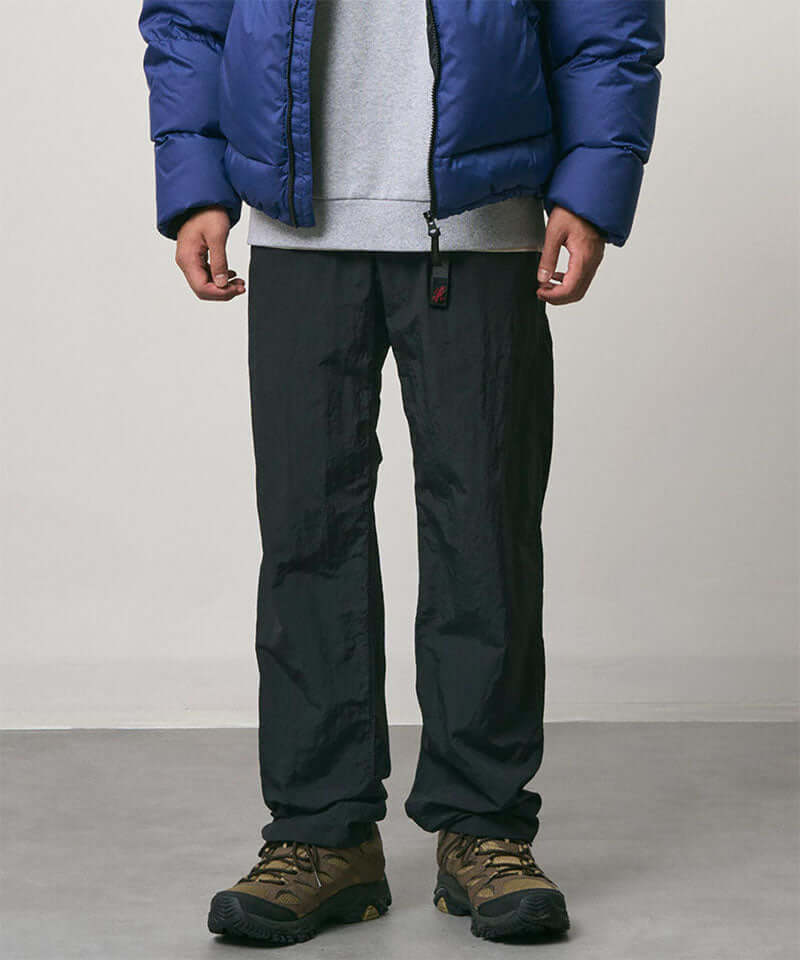 Model wearing black Nylon Gramicci Pants and a blue jacket on a light-tone background.