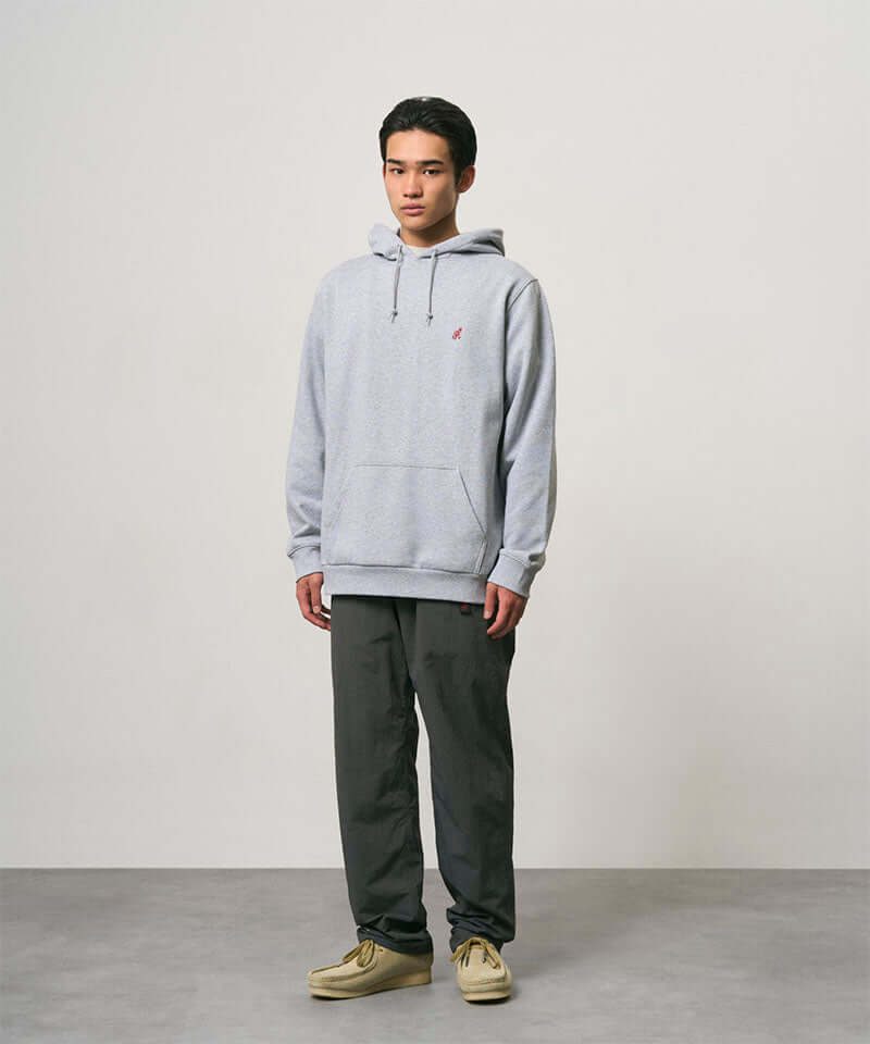 Model wearing carbon colored Nylon Gramicci Pants and a grey hoodie on a light-tone background.