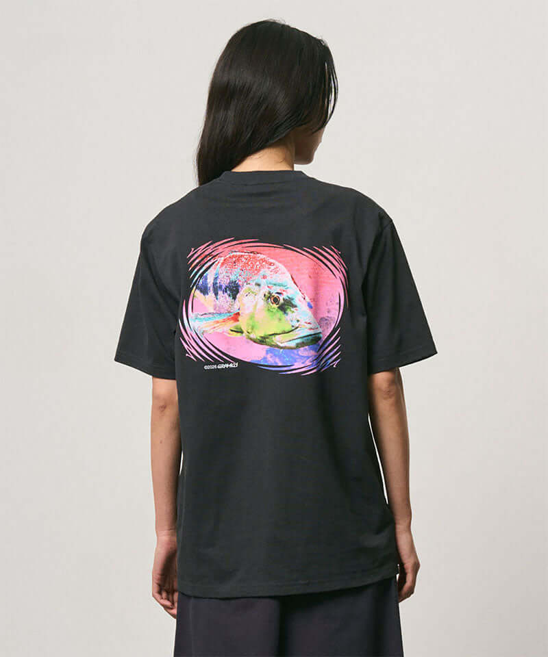 Back view of a model wearing a Gramicci vintage black Bass Tee with a graphic against a light-tone background.