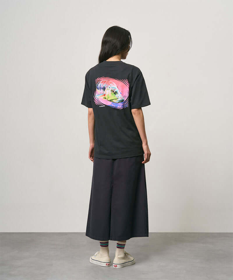 Back view of a model wearing a vintage black Gramicci Bass Tee with a graphic and black skirt on a light-tone background.