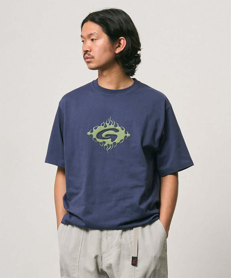 Model wearing a Gramicci navy Flames Tee with a graphic against a light-tone background.