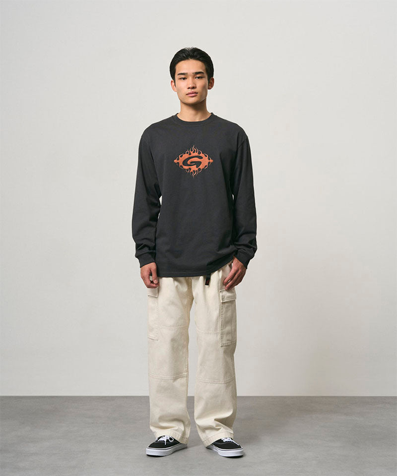 Model wearing a vintage black Gramicci Flames Long Sleeve Tee with a graphic and creme colored pants on a light-tone background.