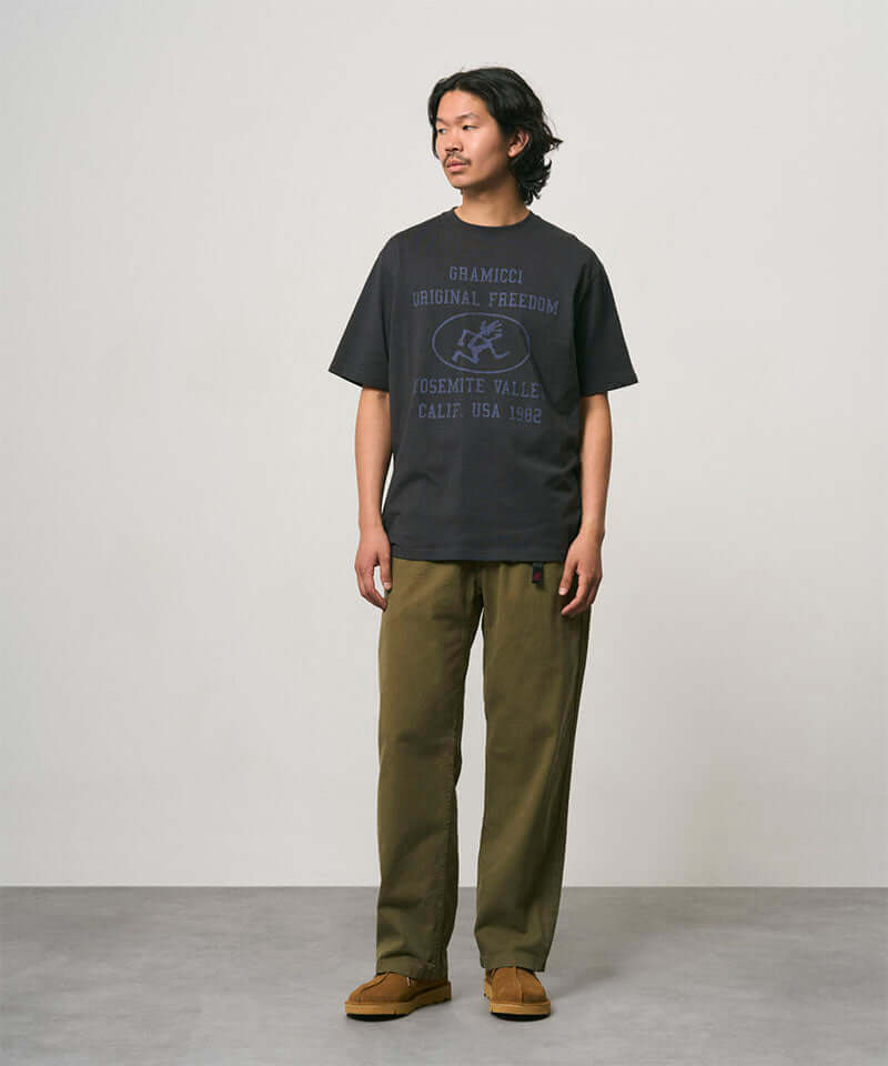 Model wearing a vintage black Gramicci Yosemite Valley Tee with a graphic and olive pants on a light-tone background.