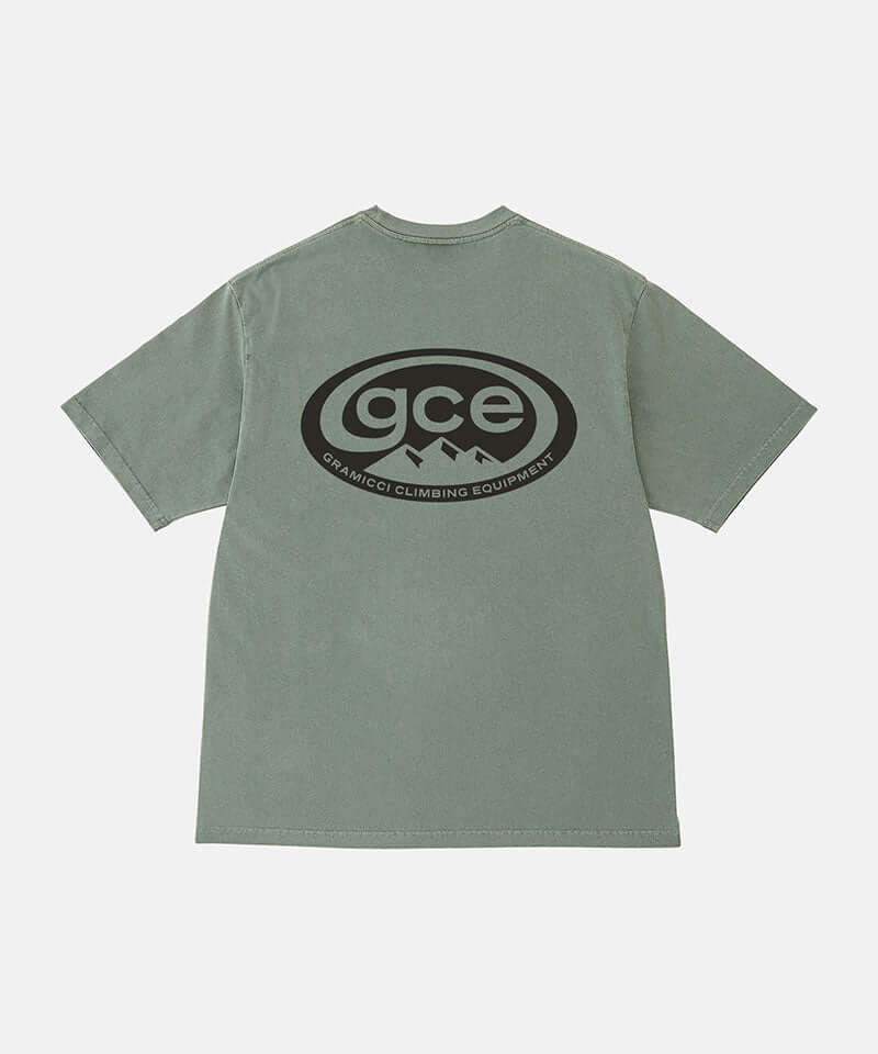 Back view of a Gramicci sage pigment colored GCE Tee Pigment Dyed with a graphic against a light-tone background.