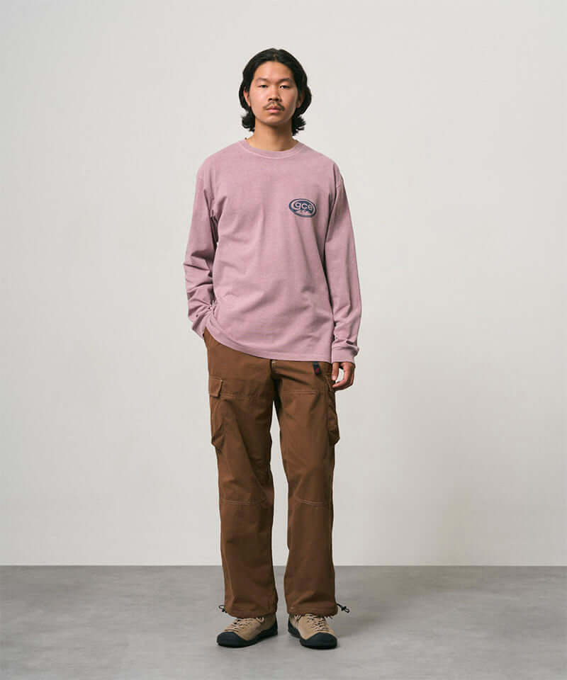 Model wearing a lilac pigment Gramicci GCE Long Sleeve Tee Pigment Dyed and brown pants on a light-tone background.