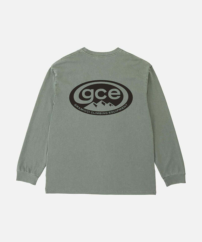 Back view of a Gramicci sage pigment colored GCE Long Sleeve Tee Pigment Dyed with a graphic against a light-tone background.