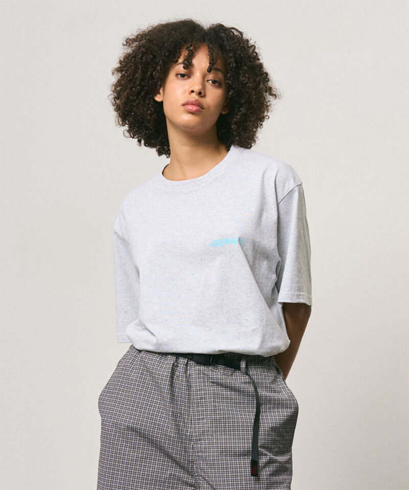 Model wearing a Gramicci ash heather color Joker Tee against a light-tone background.