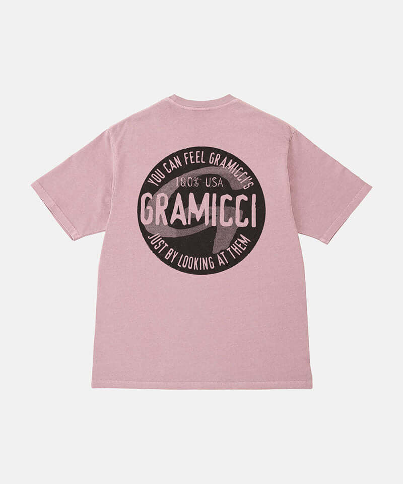 Back view of a Gramicci lilac pigment colored Icon Tee Pigment Dyed with a graphic against a light-tone background.