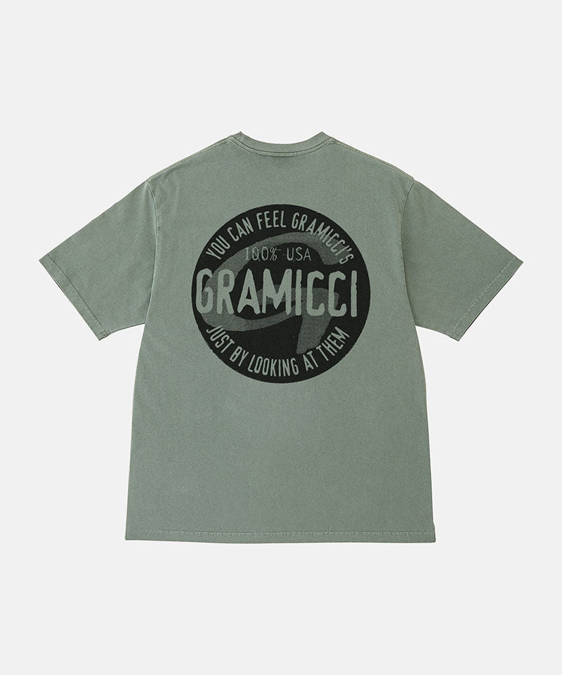 Back view of a Gramicci sage pigment colored Icon Tee Pigment Dyed with a graphic against a light-tone background.