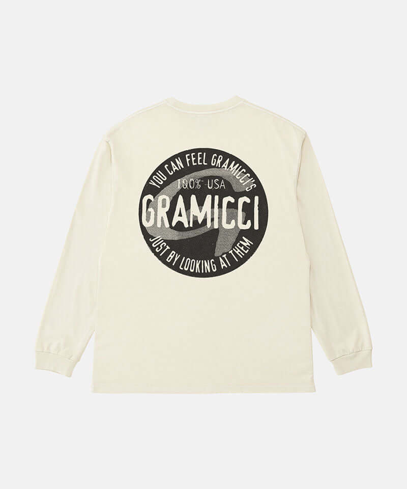 Back view of a Gramicci natural pigment colored Icon Long Sleeve Tee Pigment Dyed with a graphic against a light-tone background.