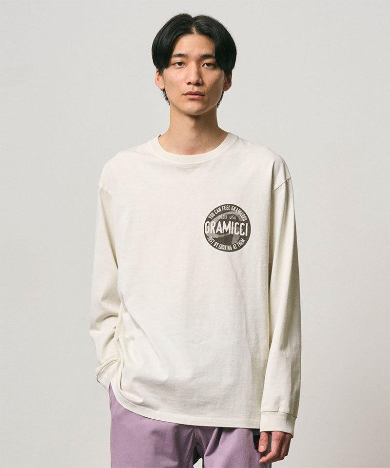 Model wearing a Gramicci natural pigment colored Icon Long Sleeve Tee Pigment Dyed with a graphic against a light-tone background.