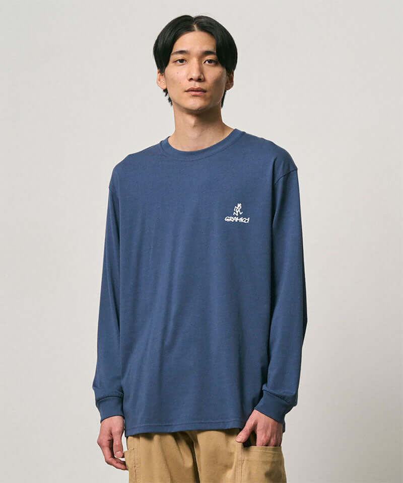 Model wearing a Gramicci dusky blue One Point Logo Long Sleeve Tee with a graphic against a light-tone background.