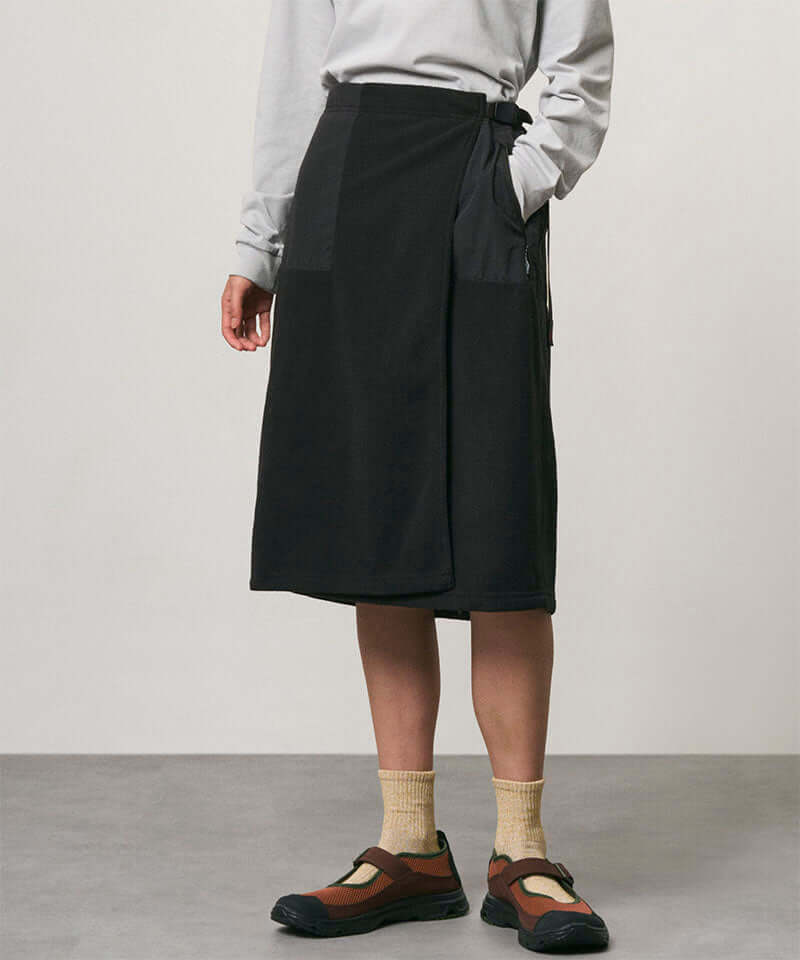 Model wearing a black Gramicci Thermal Fleece Skirt and a grey sweatshirt on a light-tone background.