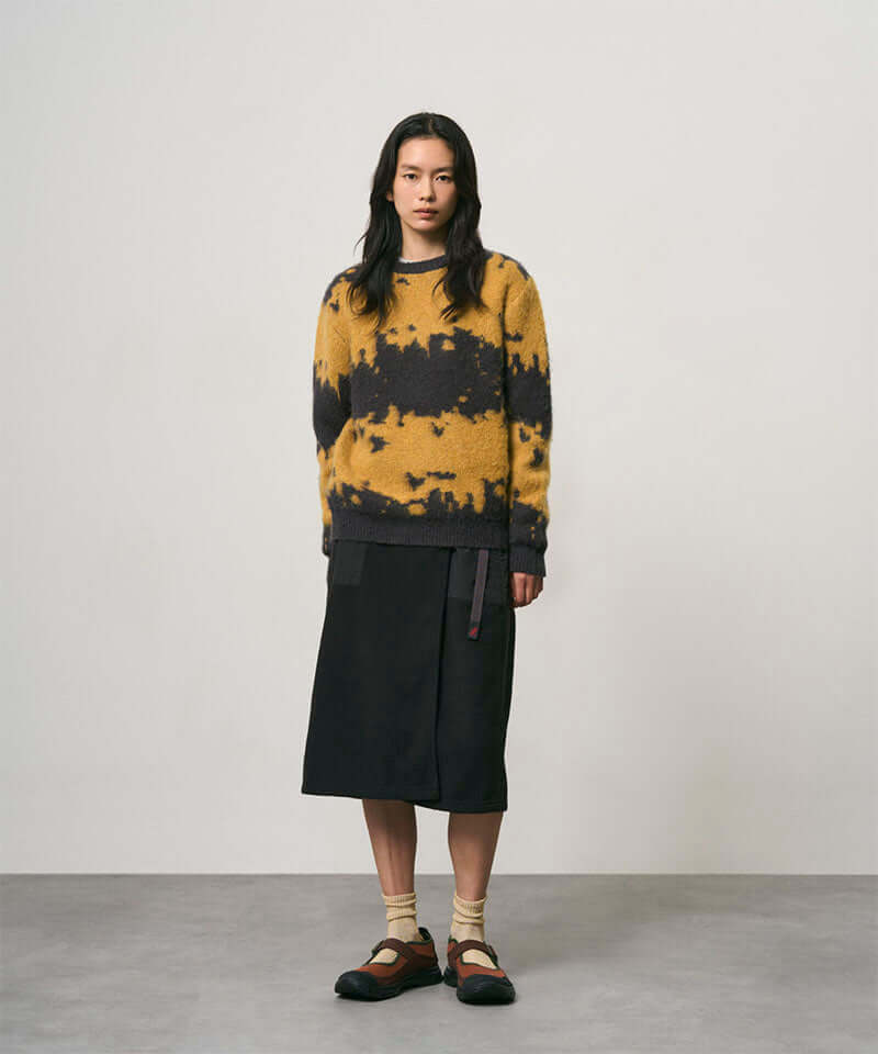 Model wearing a black Gramicci Thermal Fleece Skirt and a orange and black sweater on a light-tone background.