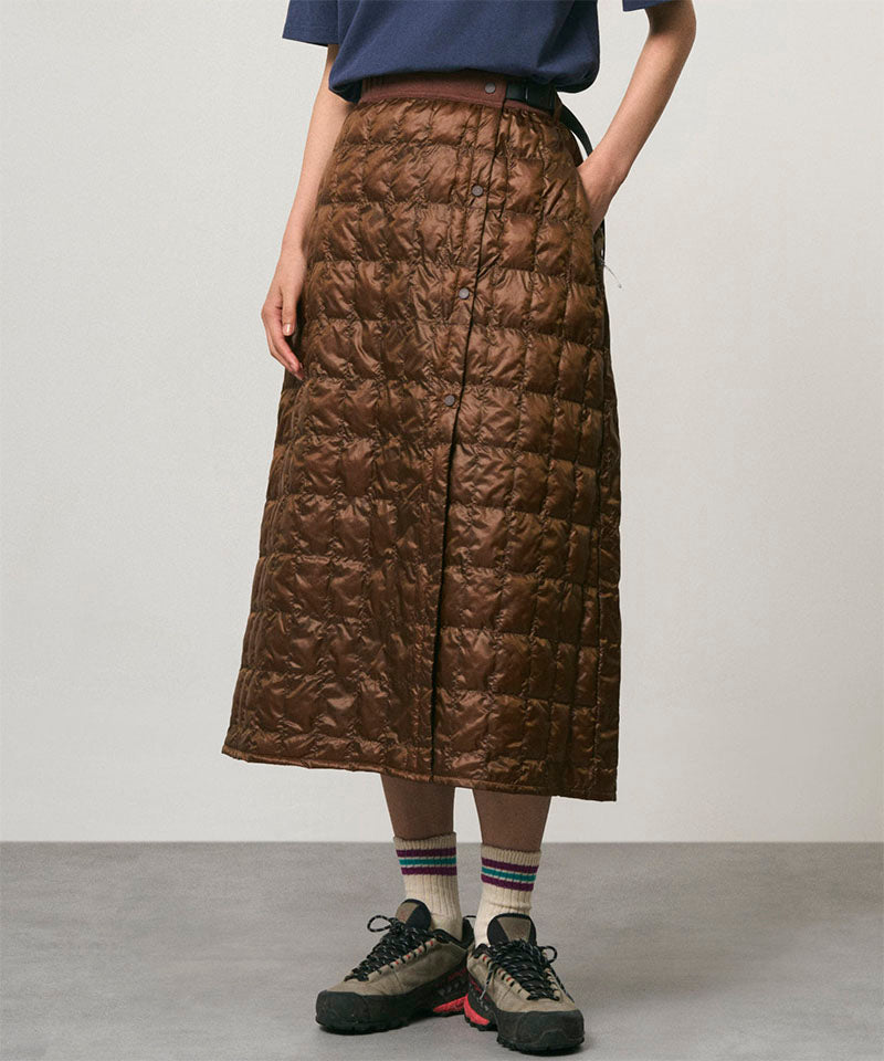 Model wearing a cola colored Gramicci G-Zero Primaloft Skirt and a blue shirt on a light-tone background.