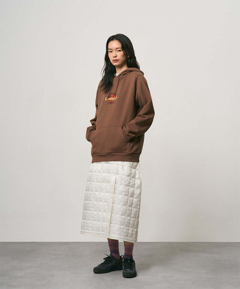 Model wearing a frost colored Gramicci G-Zero Primaloft Skirt and a brown hoodie on a light-tone background.