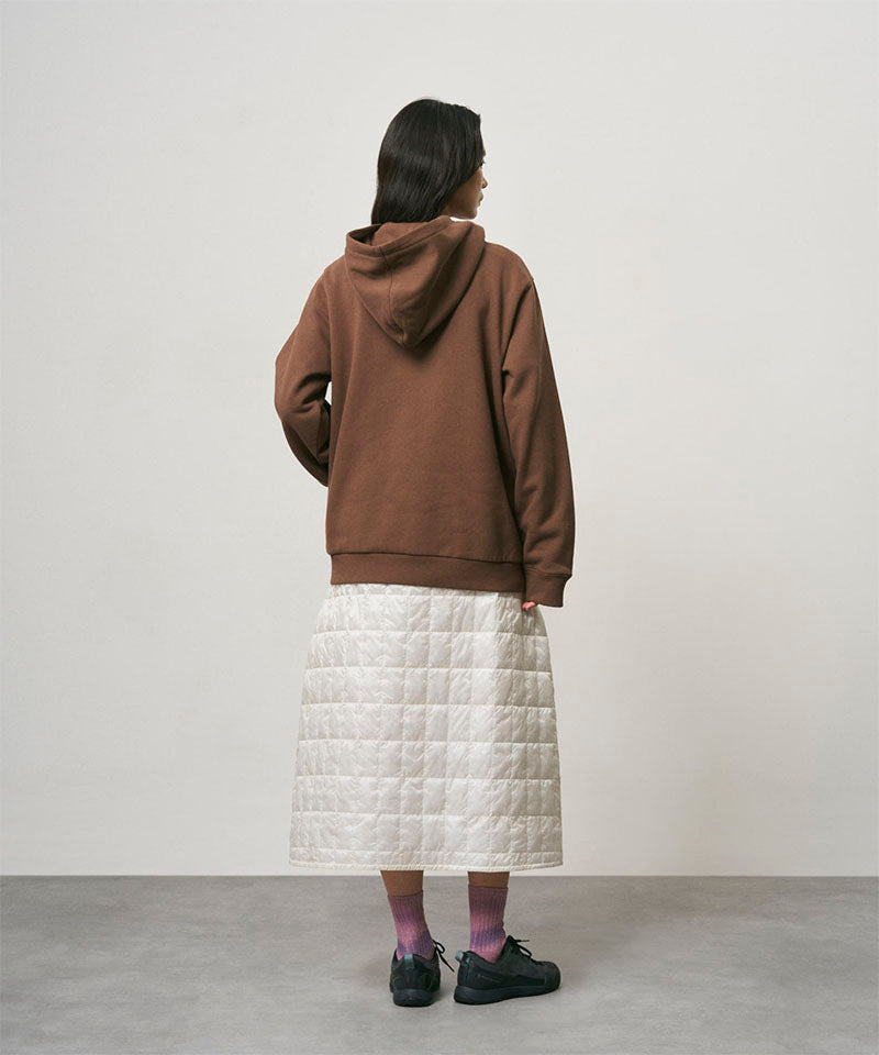 Back view of a model wearing a frost colored Gramicci G-Zero Primaloft Skirt and a brown hoodie on a light-tone background.