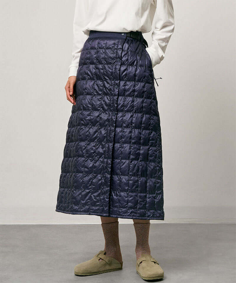 Model wearing a indigo Gramicci G-Zero Primaloft Skirt and a white shirt on a light-tone background.