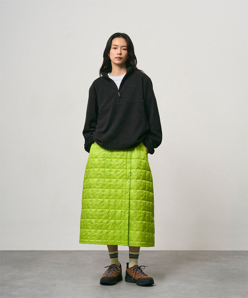 Model wearing a lime colored Gramicci G-Zero Primaloft Skirt and a black jacket on a light-tone background.