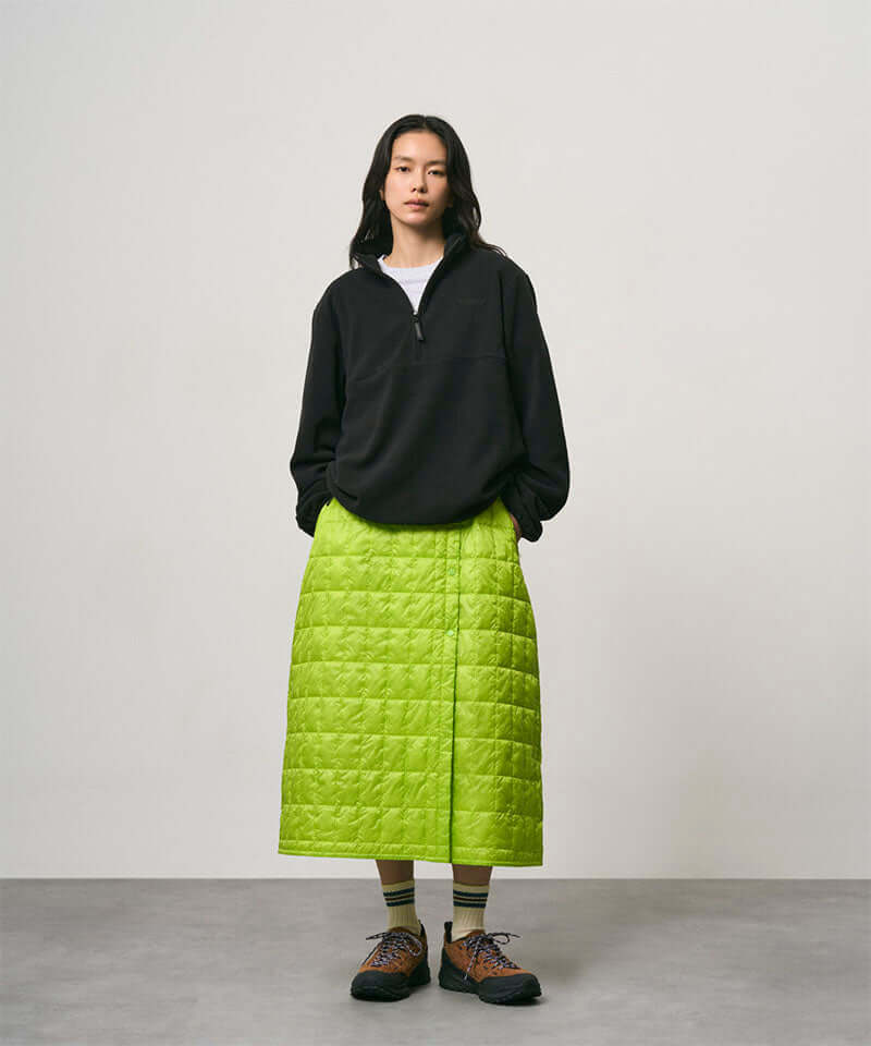 Model wearing a lime colored Gramicci G-Zero Primaloft Skirt and a black jacket on a light-tone background.