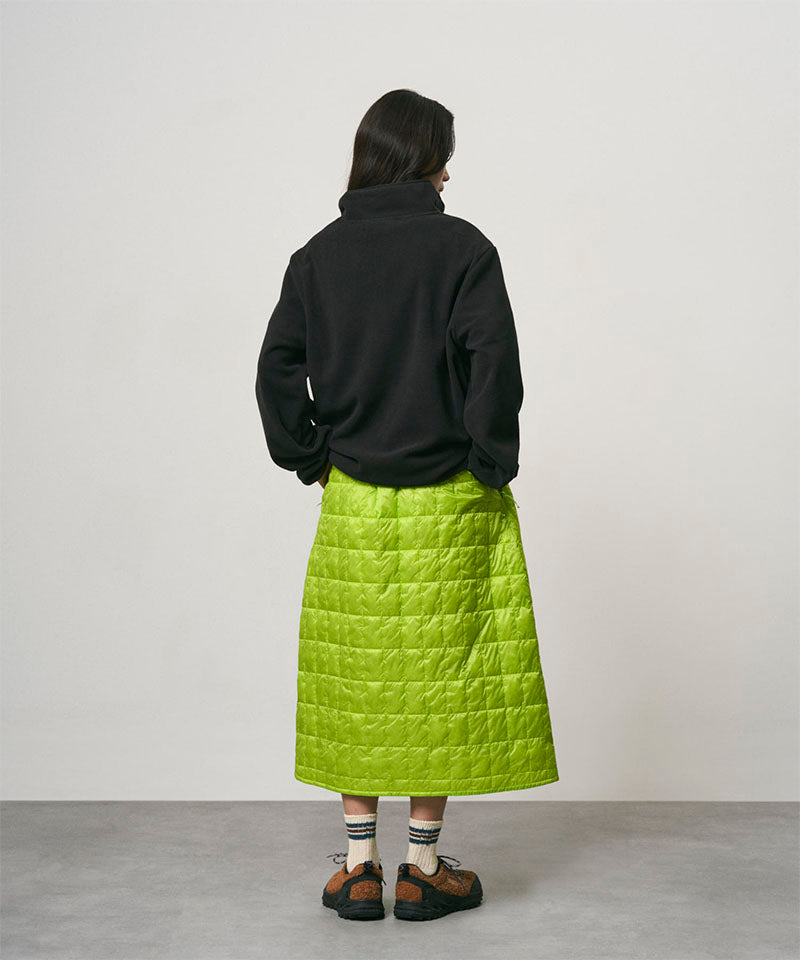 Model wearing a lime colored Gramicci G-Zero Primaloft Skirt and a black jacket on a light-tone background.