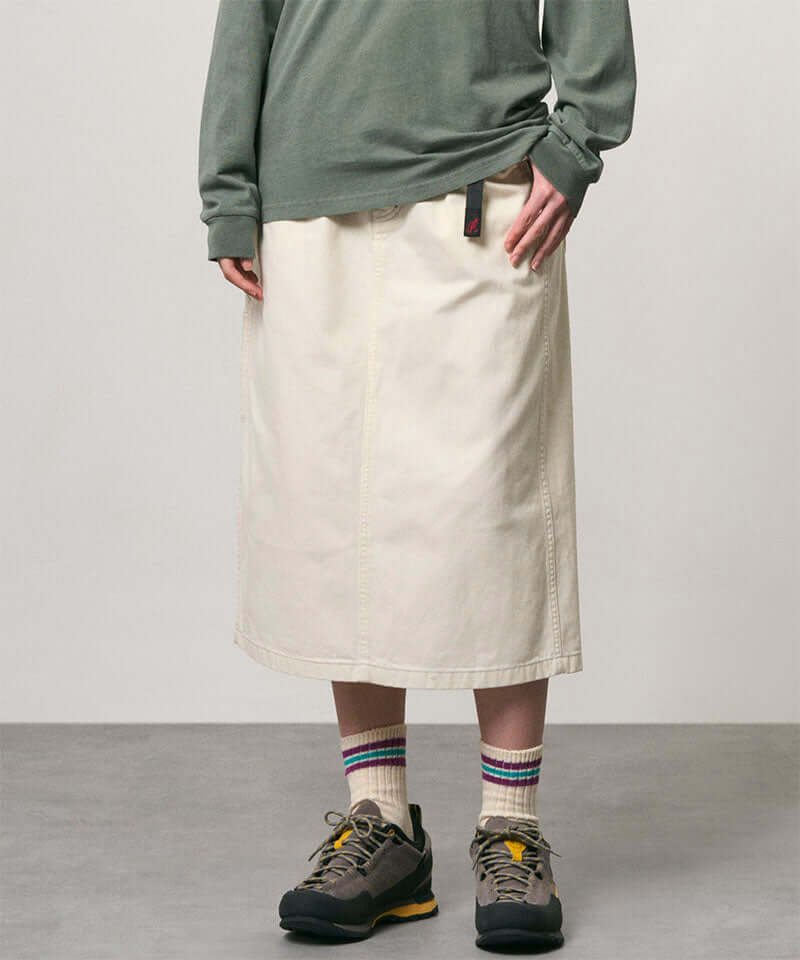 Model wearing a bone colored Gramicci Denim Carpenter Skirt and a olive shirt on a light-tone background.