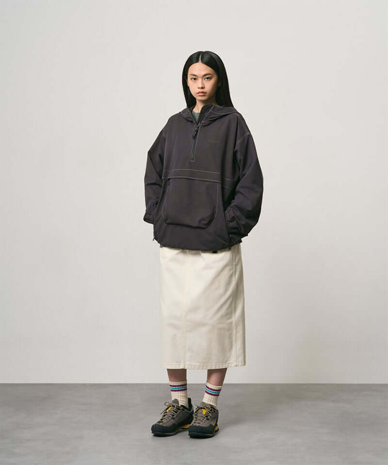 Model wearing a bone colored Gramicci Denim Carpenter Skirt and a dark brown jacket on a light-tone background.